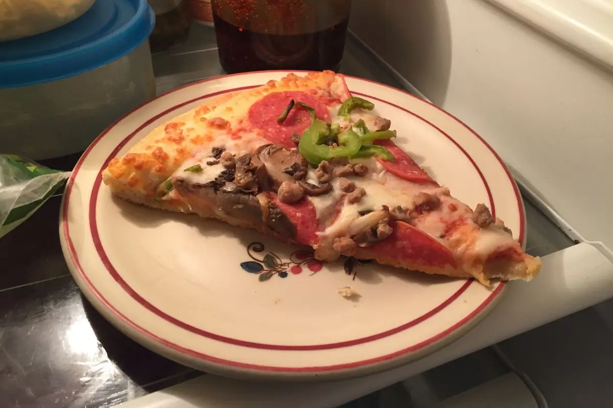 Pizza em um prato dentro da geladeira.